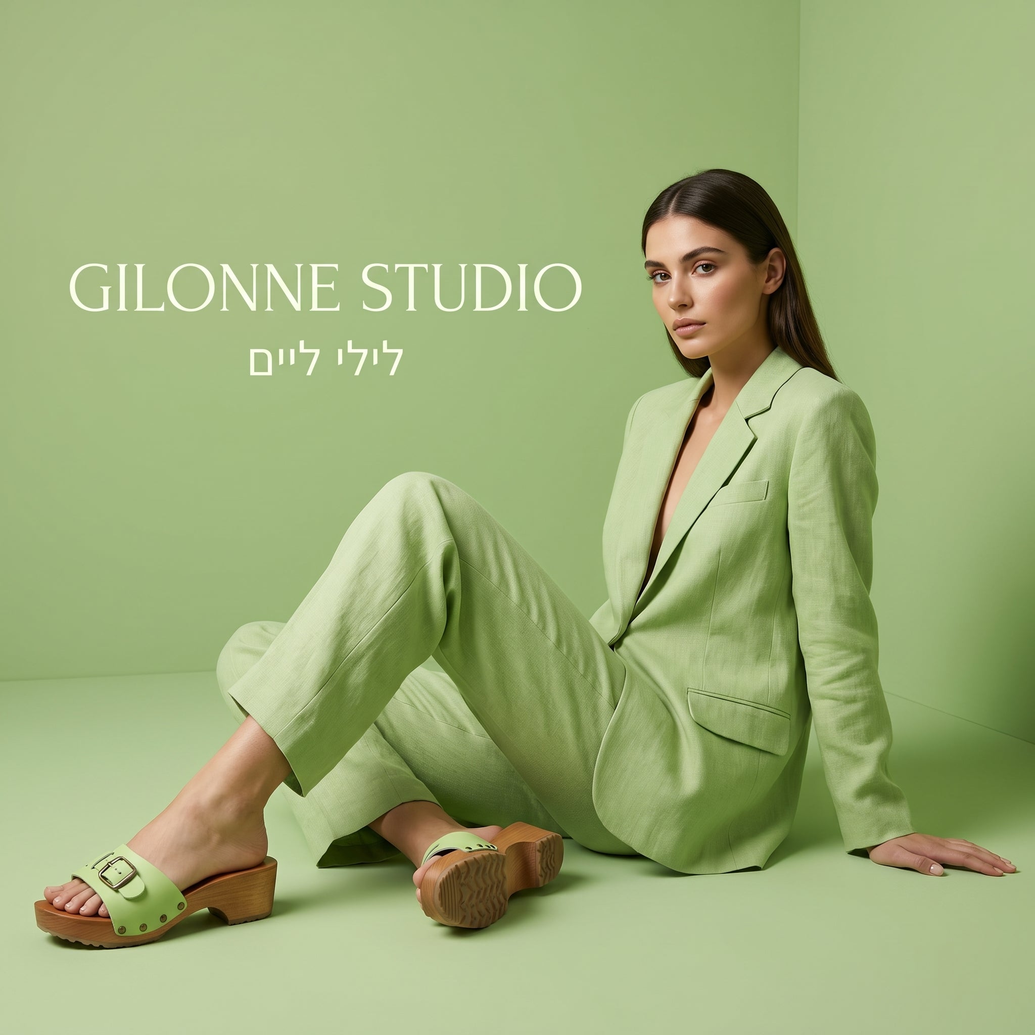 דוגמנית לבושה חליפה אלגנטית בצבע ליים, על רקע חדר כל-ליים ונועלת קבקבי עץ בצבע תואם - ליים, של ג׳ילון סטודיו