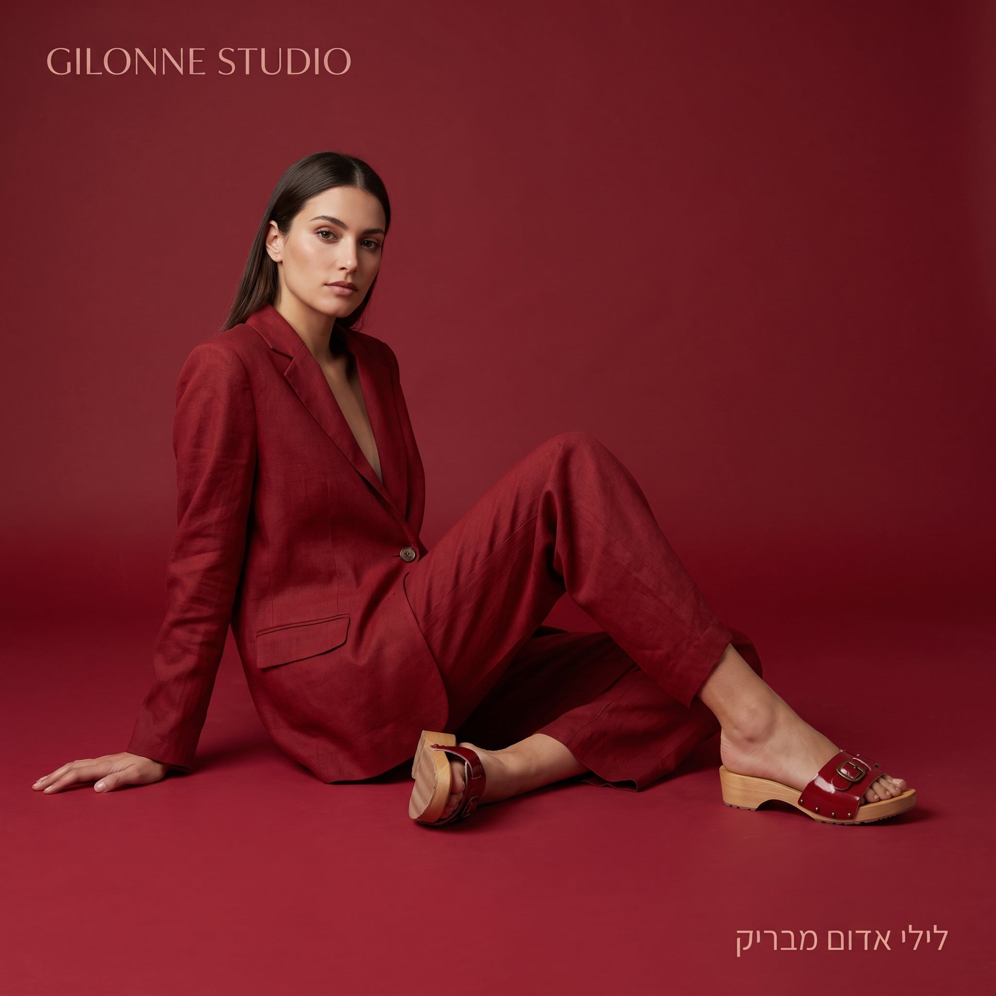 דוגמנית על רקע כל אדום, לבושה חליפה אלגנטית אדומה ונועלת קבקב עץ נמוך פתוח בצבע אדום מבריק עז של גילון סטודיו יבוא משוודיה